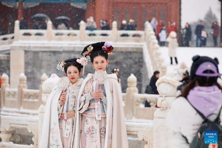 นักท่องเที่ยวเยี่ยมชมพระราชวังต้องห้ามท่ามกลางหิมะตกในกรุงปักกิ่ง เมืองหลวงของประเทศจีน เมื่อวันที่ 13 ธันวาคม 2566 (ซินหัว)