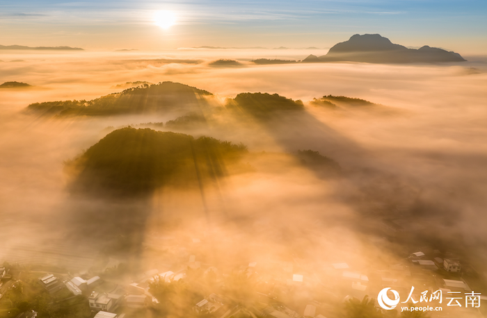 ภาพถ่ายแสดงให้เห็นพระอาทิตย์ขึ้นอันน่าทึ่งเหนือทะเลเมฆ และหมู่บ้านอันเงียบสงบในอำเภอหนิงเอ่อร์ เมืองผู่เอ่อร์ มณฑลยูนนาน ภาคตะวันตกเฉียงใต้ของจีน (ภาพโดย เหรา เสวี่ยซง)