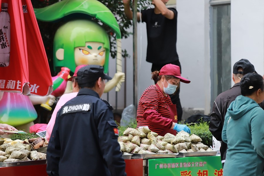นักท่องเที่ยวซื้อบ๊ะจ่างที่ตลาดอาหารในงานวัดปัวหลัวตั้น เมืองกว่างโจว มณฑลกวางตุ้ง ทางตอนใต้ของจีน  (พีเพิลส์ เดลี่ ออนไลน์)